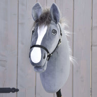 Hobby Horse Beauty mit Schwarzem Halfter von Hobby Horse LarDen ist ein graues Plüsch-Hobby Horse mit schwarzem Zaumzeug, weißer Blesse und flauschiger Mähne, inspiriert von einem englischen Vollbluthengst, vor hellem Holzbackground.