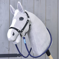 Reins Blues de Hobby Horse LarDen, Hobby Horse en peluche gris avec bride noire, rênes faites main, longe bleue et marques blanches sur le visage, monté sur un bâton en bois, présenté devant un mur en bois gris.