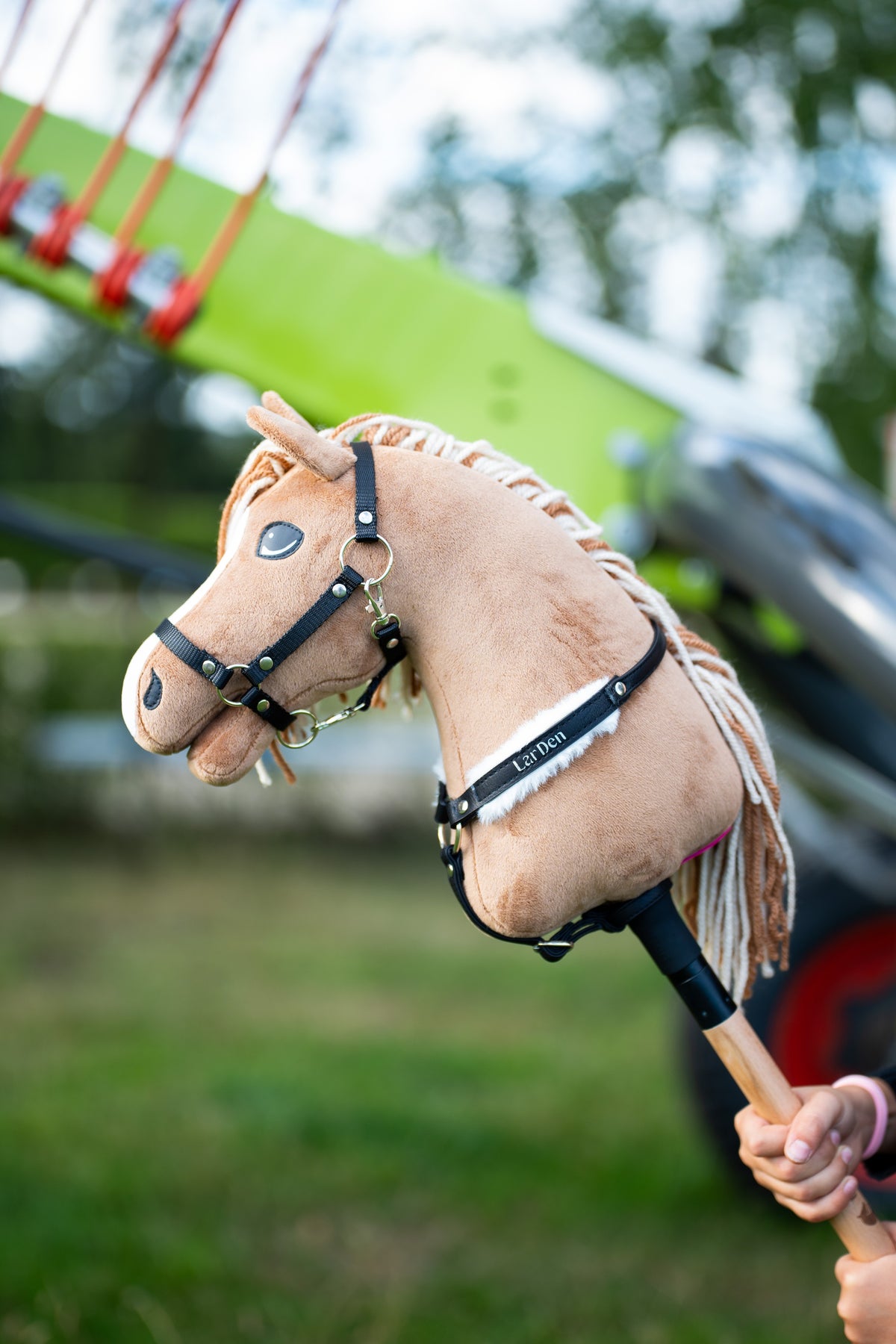 Hobby Horse Sandy mit schwarzem Brustgurt aus Kunstleder und weißem Fellbesatz im Freien