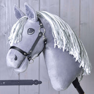 Hobby Horse Calypso mit Schwarzem Halfter von Hobby Horse LarDen, inspiriert vom Niederländischen Warmblut, mit grauem Fell und weißer Garnmähne, auf einem Stab vor einer hellgrauen Holzwand.