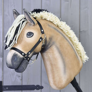 Hobby Horse Colby mit Schwarzem Halfter von Hobby Horse LarDen mit hellbraunem Körper, creme-schwarzer Garnmähne und schwarzem Halfter, vor hellgrauem Holzhintergrund.