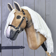 Hobby Horse Connie mit Schwarzem Halfter von Hobby Horse LarDen mit realistischem hellbraunem Gesicht, weißer Blesse, schwarzem Halfter für Hobby Horse und langer weißer Garnmähne auf einem Holzstab, vor einer grauen Holzwand gezeigt.