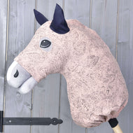 Combinaison de protection Hobby Horse Cosmos (Lycra) de Hobby Horse LarDen en rose et blanc, avec oreilles foncées, montrée montée sur un bâton en bois devant un mur en bois gris clair.