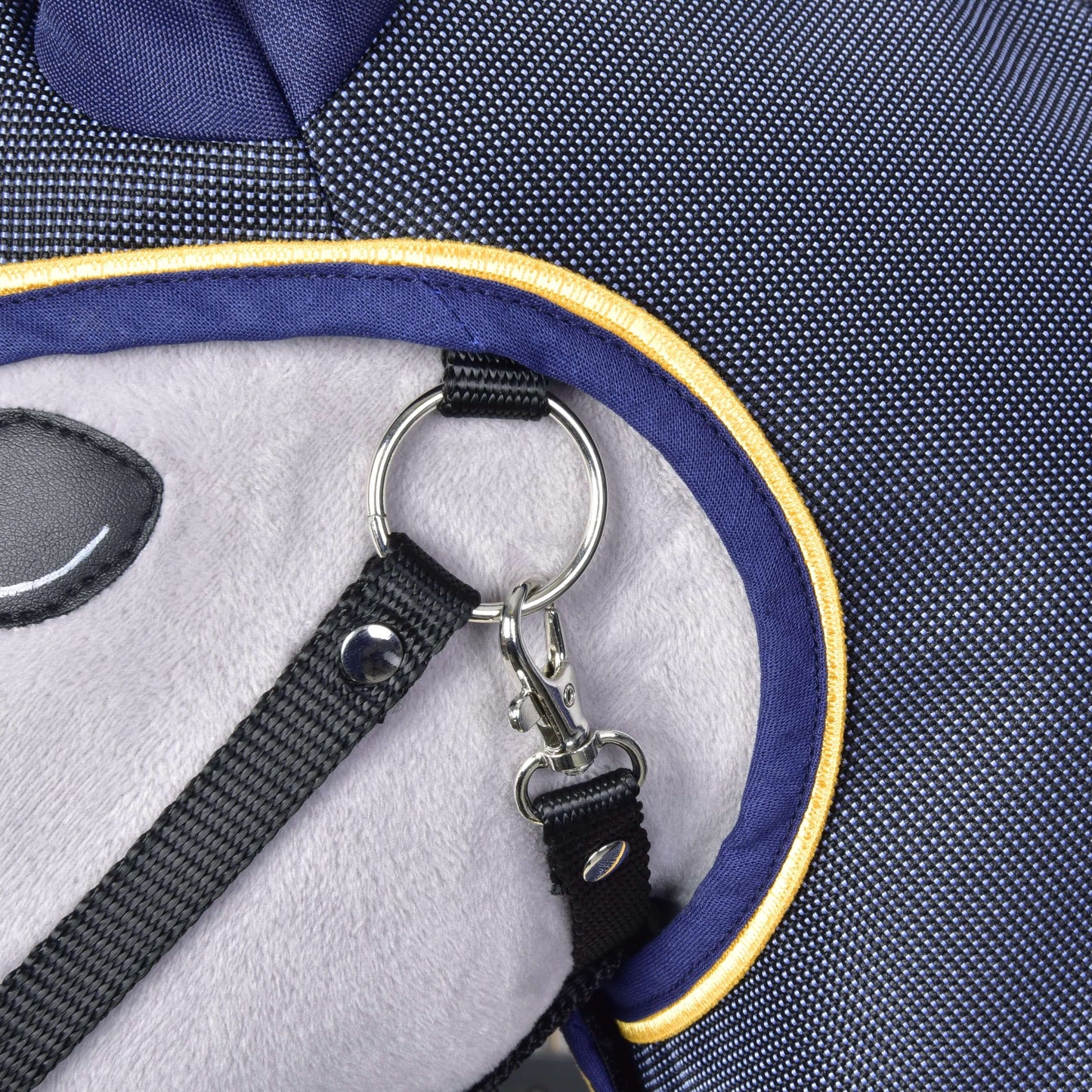 Nahaufnahme einer Stofftasche mit Plüschpaneel, dunkelblauer Einfassung, gelber Paspel und Metall-D-Ring-Verschluss, der einen schwarzen Riemen sichert – ideal zum Tragen deiner Hobby Horse LarDen Regendecke Crone oder von Hobby Horse Accessoires bei jedem Abenteuer.