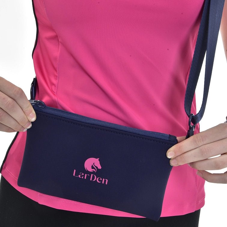 Personne portant un haut rose et tenant une pochette bleue marine zippée avec bandoulière. La pochette, parfaite pour les fans de Hobby Horsing, comporte un logo de cheval rose et le mot LarDen imprimé dessus.