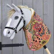 The Hobby Horse LarDen "Blanket Jungle" is a plush hobby horse with a grey head, black bridle, and a colorful blanket body—ideal for imaginative play or early horse training—shown against a wooden panel background.