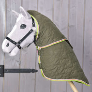 A gray hobby horse with a black bridle wears the Hobby Horse LarDen "Blanket with removable neck cover Rubby," a green, high-quality blanket with heart patterns and colorful trim, displayed against a wooden wall.