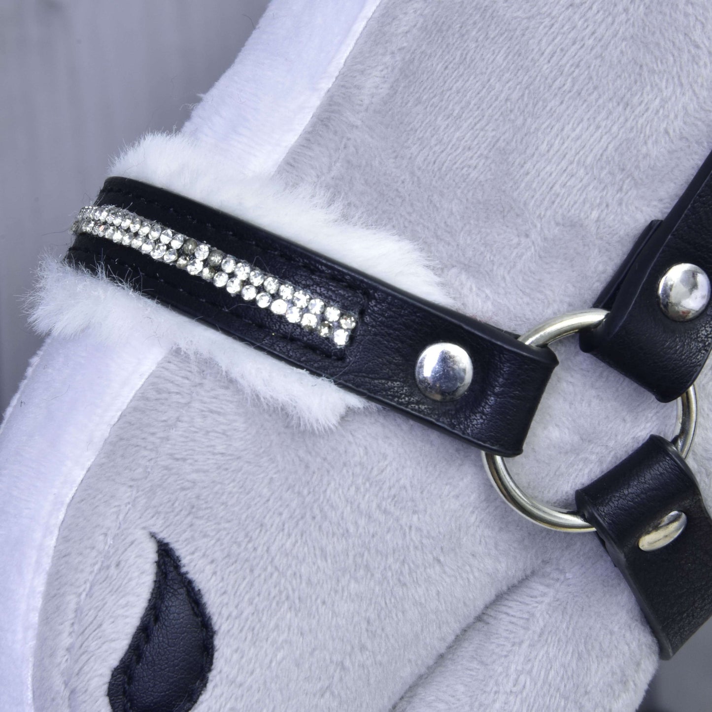 Close-up of a plush horse toy wearing the Hobby Horse LarDen Halter with fur - leatherette Espresso, featuring white faux fur trim, sparkling rhinestones, silver hardware, and part of the toy’s stitched eye.
