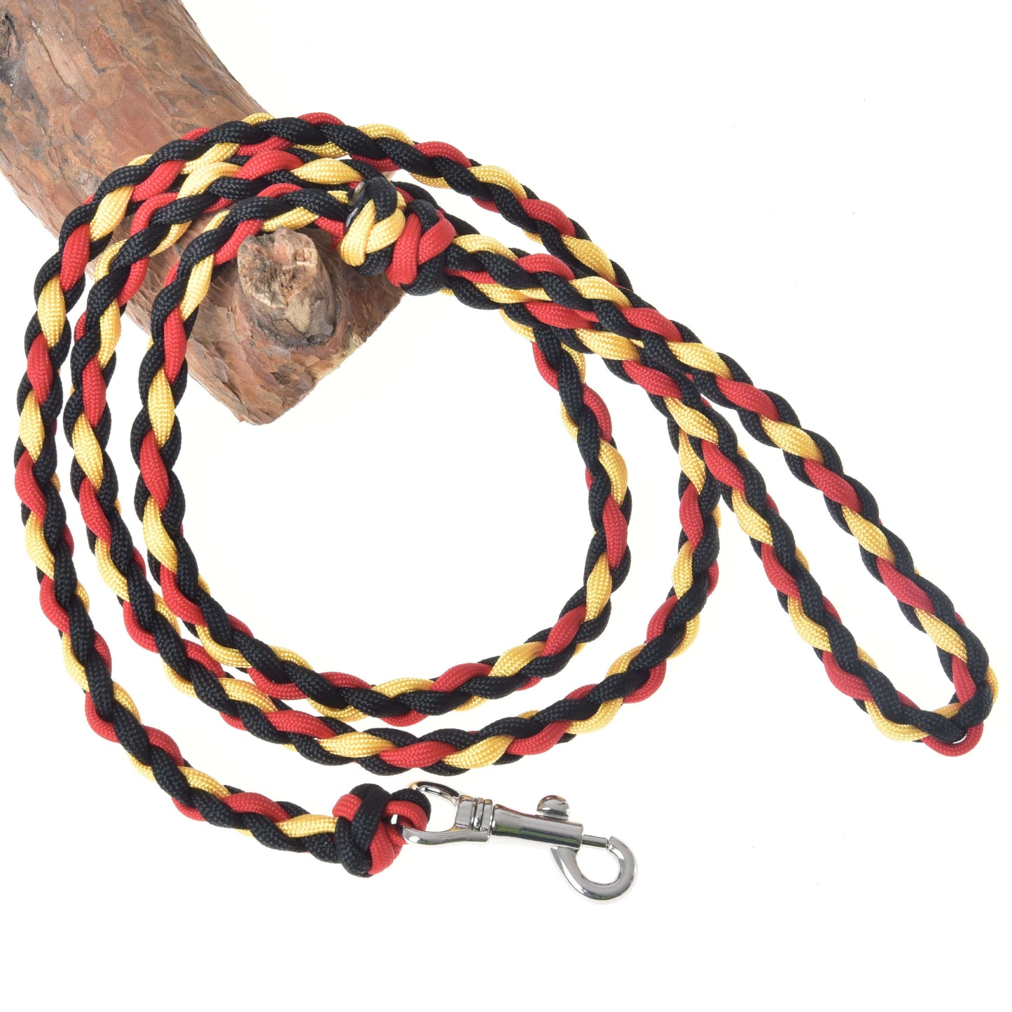 Hobby Horse LarDen Hobby Horse - Führstrick Flag ist eine geflochtene Leine mit schwarzen, roten und gelben Strängen, einem robusten Metallverschluss und ordentlich auf hellem Holz aufgewickelt – perfekt für Hunde oder zum Spielen mit Hobby Horse.
