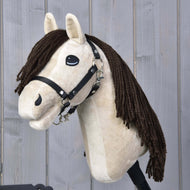 Hobby Horse Frederik LD mit Schwarzem Halfter von Hobby Horse LarDen mit beigem Gesicht, schwarzem Halfter und langer brauner Garnmähne vor einem hellgrauen Holzhintergrund.