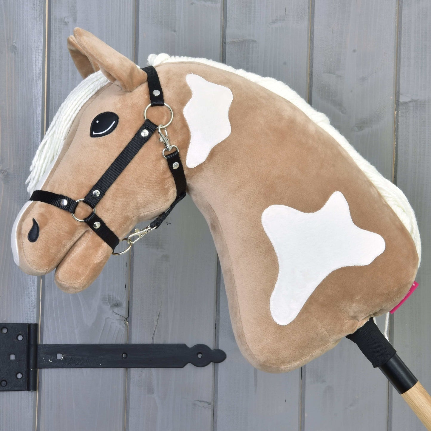 Hobby Horse Fury avec licol noir de Hobby Horse LarDen, avec corps marron clair, crinière blanche et taches sur un bâton en bois. Il comprend un licol noir et un œil cousu, idéal pour des balades imaginatives sur les sentiers.