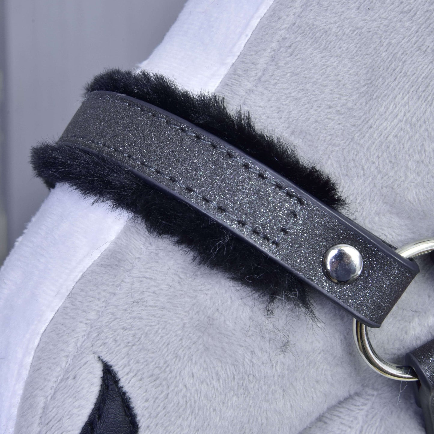 Gros plan sur le licol avec fourrure - similicuir Graphite complet de Hobby Horse LarDen, montrant un tissu en peluche gris graphite, une sangle noire en similicuir avec coutures et anneau métallique, ainsi que des accents blancs et noirs pour un licol élégant pour hobby horse.