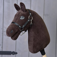 Construis ton cheval avec une tête brun foncé en peluche, une crinière noire en fil, une bride noire et des rênes, monté sur un bâton en bois et présenté devant des panneaux en bois gris.