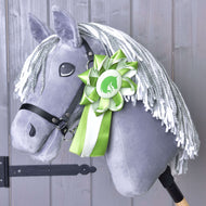 Die Hobby Horse LarDen Hobby Horse Schleife Green NEW ist an einem grauen Plüsch-Hobby Horse mit weißer Garnmähne, schwarzem Zaumzeug und einer grün-weißen Schleife am Hals vor Holzhintergrund zu sehen.