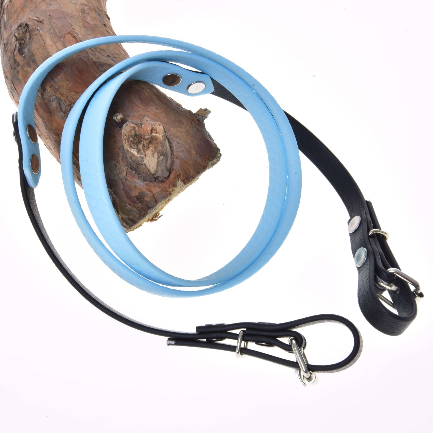Gummierte Zügel - Light blue von Hobby Horse LarDen aus hellblauem und schwarzem Leder mit Metallschnalle und von Zäumungen inspiriertem Design, um Holz gewickelt und vor weißem Hintergrund gezeigt.
