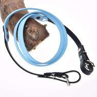 Gummierte Zügel - Light blue von Hobby Horse LarDen aus hellblauem und schwarzem Leder mit Metallschnalle und von Zäumungen inspiriertem Design, um Holz gewickelt und vor weißem Hintergrund gezeigt.