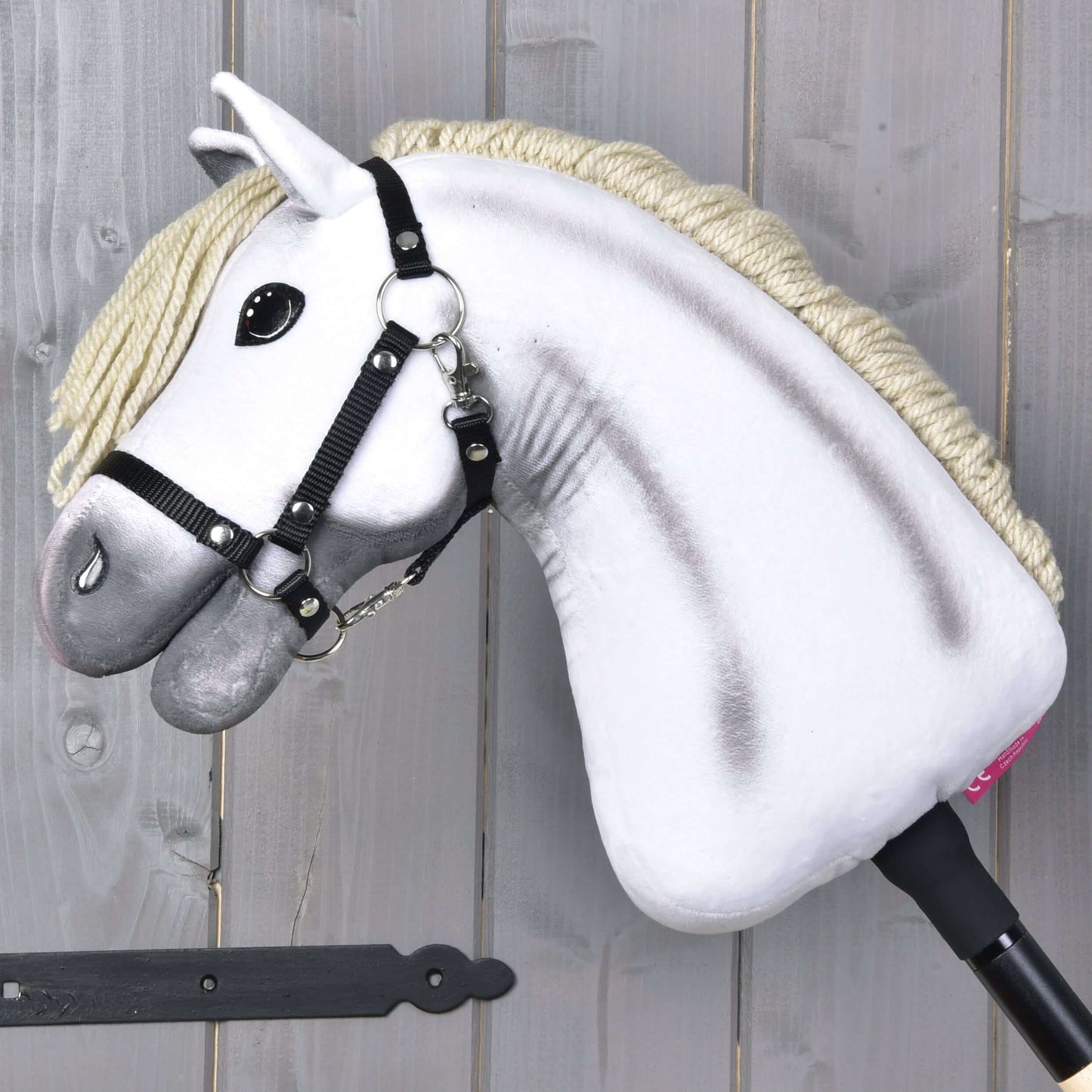 Hobby Horse Little Lady mit Schwarzem Halfter von Hobby Horse LarDen mit weißem Plüschkopf, schwarzem Halfter und cremefarbener Mähne, auf einem schwarzen Stock – ideal als Spielzeug für fantasievolles Spiel.