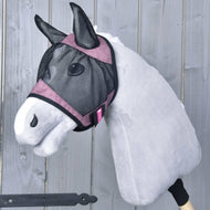 Die Hobby Horse LarDen Fliegenmaske de Luxe Pink, ein graues Stoff-Hobby Horse mit rosa Besatz und waschbarer Fliegenmaske, ist auf einem Holzstab montiert und vor einem Hintergrund aus Holzplanken zu sehen.