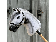 Hobby Horse Naivy mit schwarzem Halfter von Hobby Horse LarDen vor einer rustikalen Holztür, mit grau-weißem Appaloosa-Design und detaillierter Mähne.