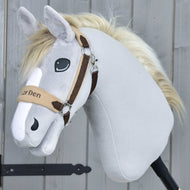 Das Hobby Horse LarDen „Fellhalfter LarDen Brown“ zeigt hellgraues Plüschfell, eine cremefarbene Mähne, ein hellbraunes und braunes Halfter mit weichem Fleece-Nasenriemen, gestickte Augen und einen freundlichen Ausdruck vor einem Holz-Hintergrund.
