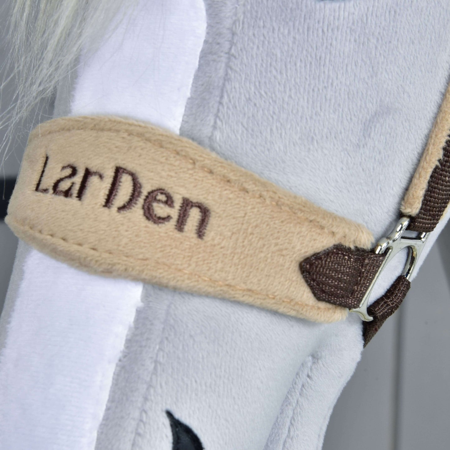 Gros plan sur le Licol en fourrure LarDen marron de Hobby Horse LarDen, avec sangle beige brodée « LarDen », accents marron, muserolle douce en polaire blanche et boucle métallique.