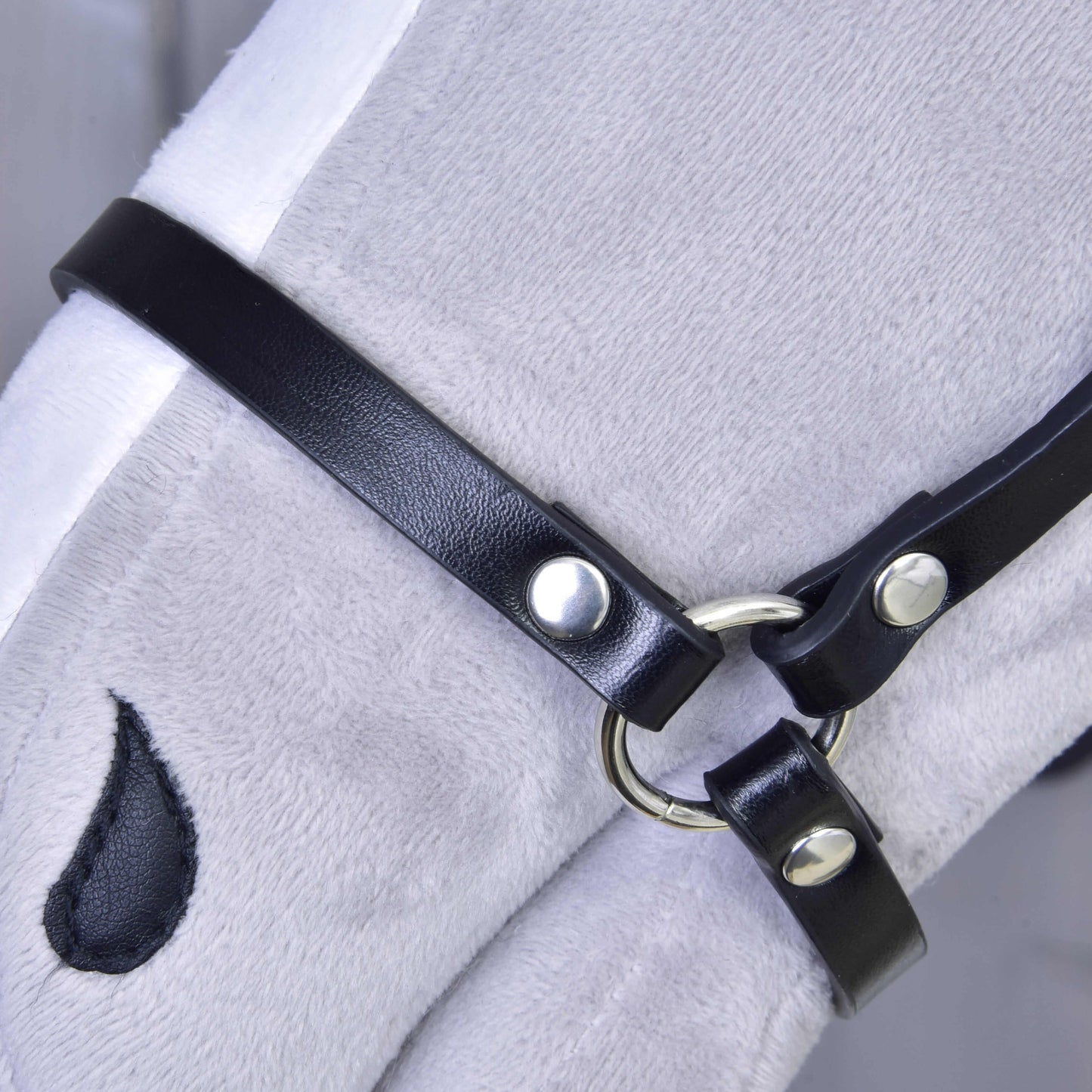 Gros plan d’un cheval jouet en peluche blanche portant le Licol - similicuir noir de Hobby Horse LarDen, avec une marque en forme de goutte sous l’œil.