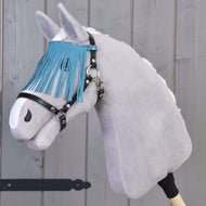 A gray Hobby Horse LarDen with a black halter featuring turquoise fringes stands in front of a wooden wall.
