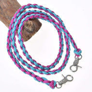 Die Hobby Horse LarDen Zügel Pinkie Blue aus blauem und rosa Polypropylenseil mit Metallkarabinern an beiden Enden sind auf einem weißen Hintergrund aufgewickelt und über braunes Holz drapiert.