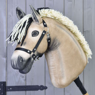 Nahaufnahme von Hobby Horse LarDens beigem Hobby Horse Ozzy mit Schwarzem Halfter mit schwarz-weißer Garnmähne, schwarzem Halfter und Knopfaugen, auf einem Stab vor grauem Holzhintergrund.