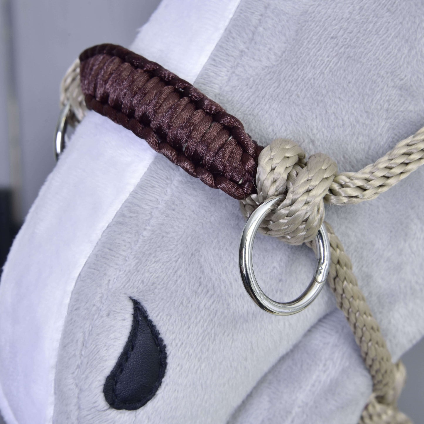 Gros plan sur le visage d’un cheval en peluche portant le Licou en corde Nature de Hobby Horse LarDen, avec tressage beige et marron, anneau métallique et détail d’œil brodé en noir.