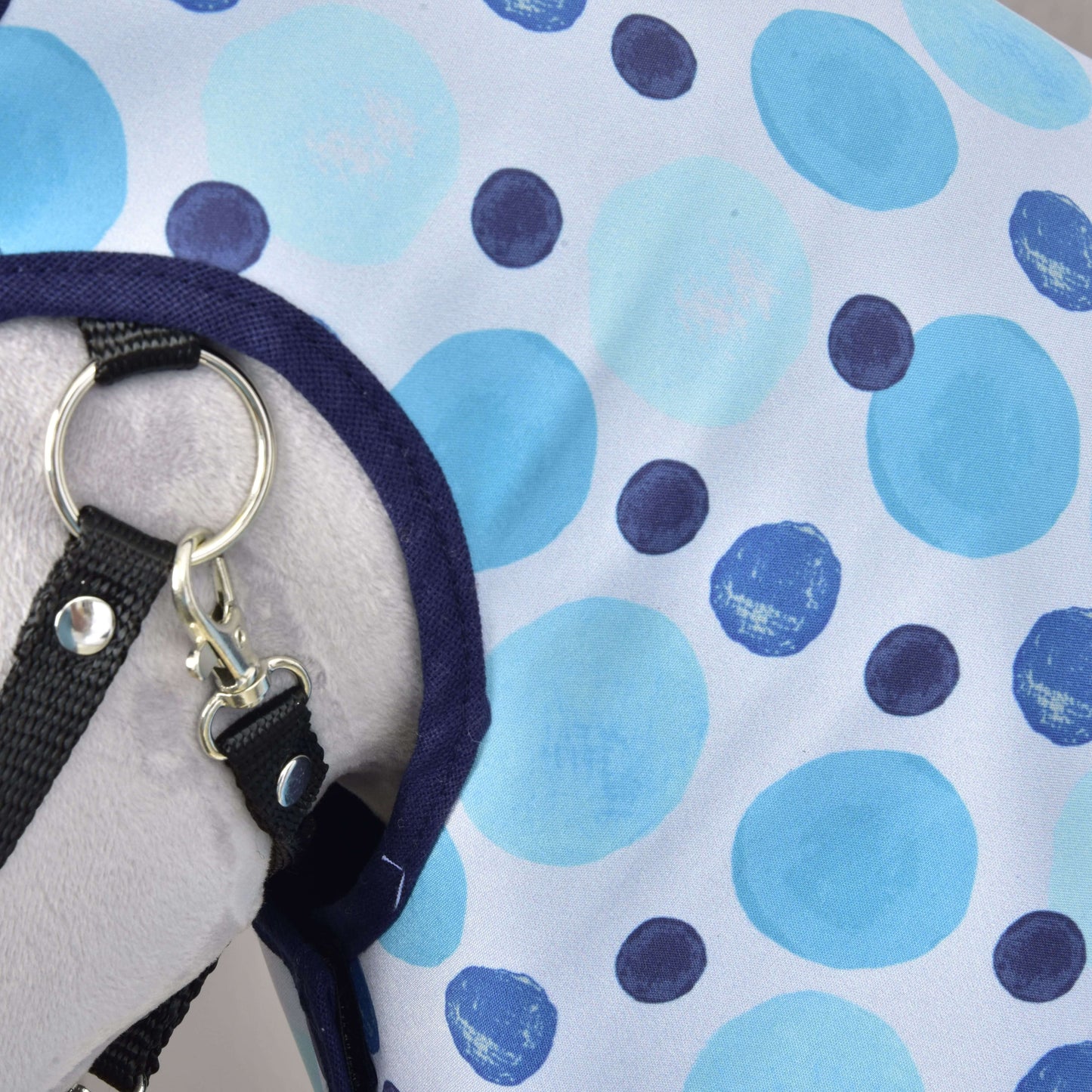 Nahaufnahme der Regendecke Bubbles von Hobby Horse LarDen mit blauem und dunkelblau gepunktetem Stoff, Metallring und Clip – ein ideales Allwetter-Accessoire für Hobby Horse, auf einer hellgrauen Oberfläche.