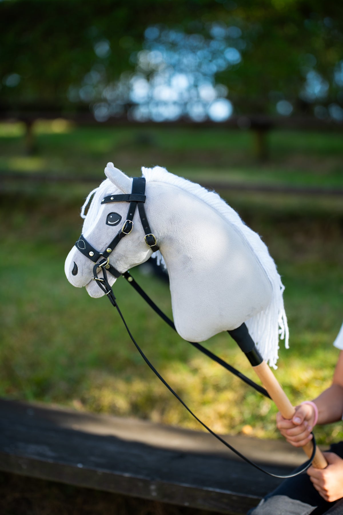 Hobby Horse Complete bitless bridle, decorated, on a light grey Hobby Horse outdoors with black reins