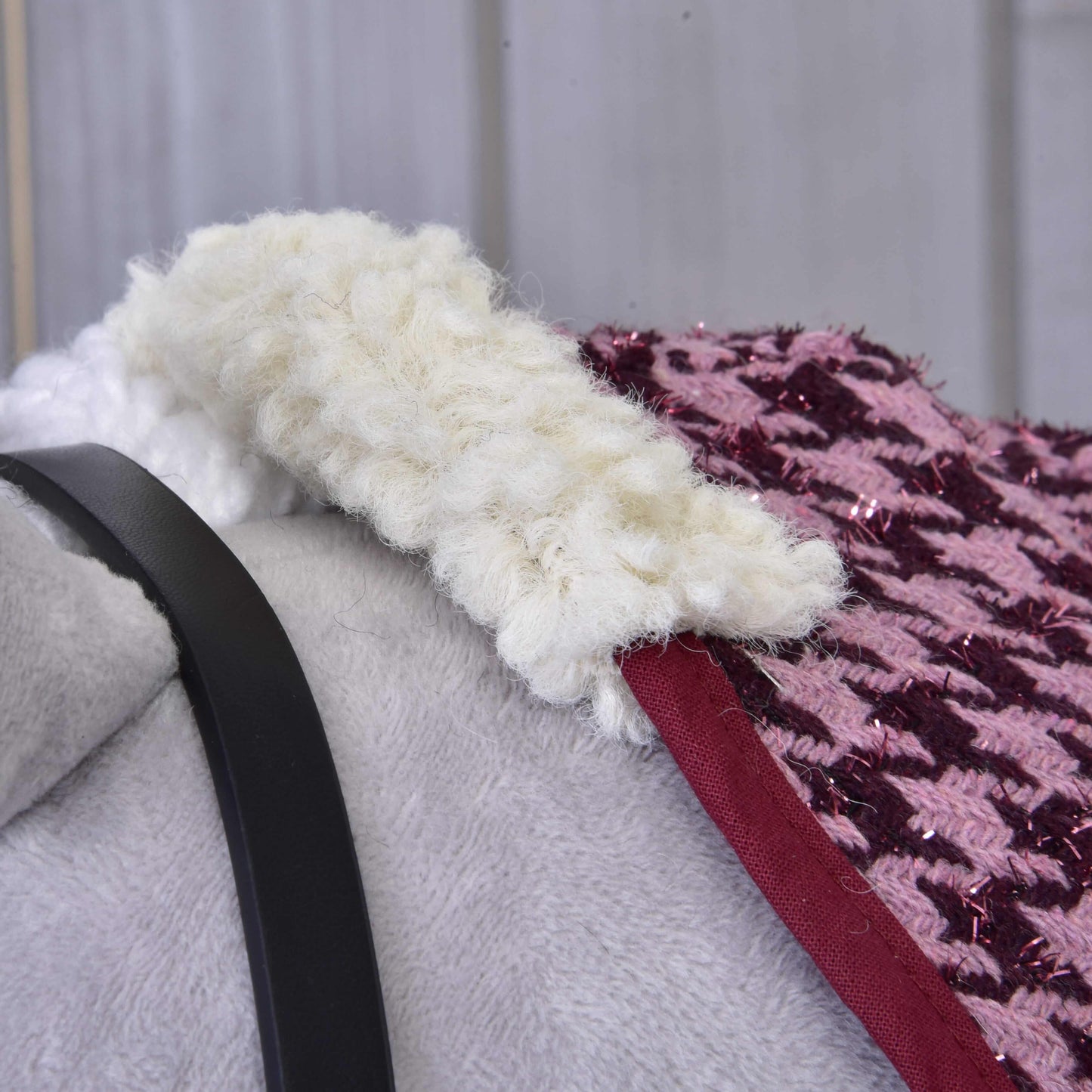 Nahaufnahme von Set Harmony Elsa von Hobby Horse LarDen – eine weiche graue Stalldecke mit schwarzem Halfterriemen, versehen mit dichtem cremefarbenem Wollbesatz und pink-lila glitzerndem Gewebe. Der warme, weich verschwommene Hintergrund ergänzt das Bild.