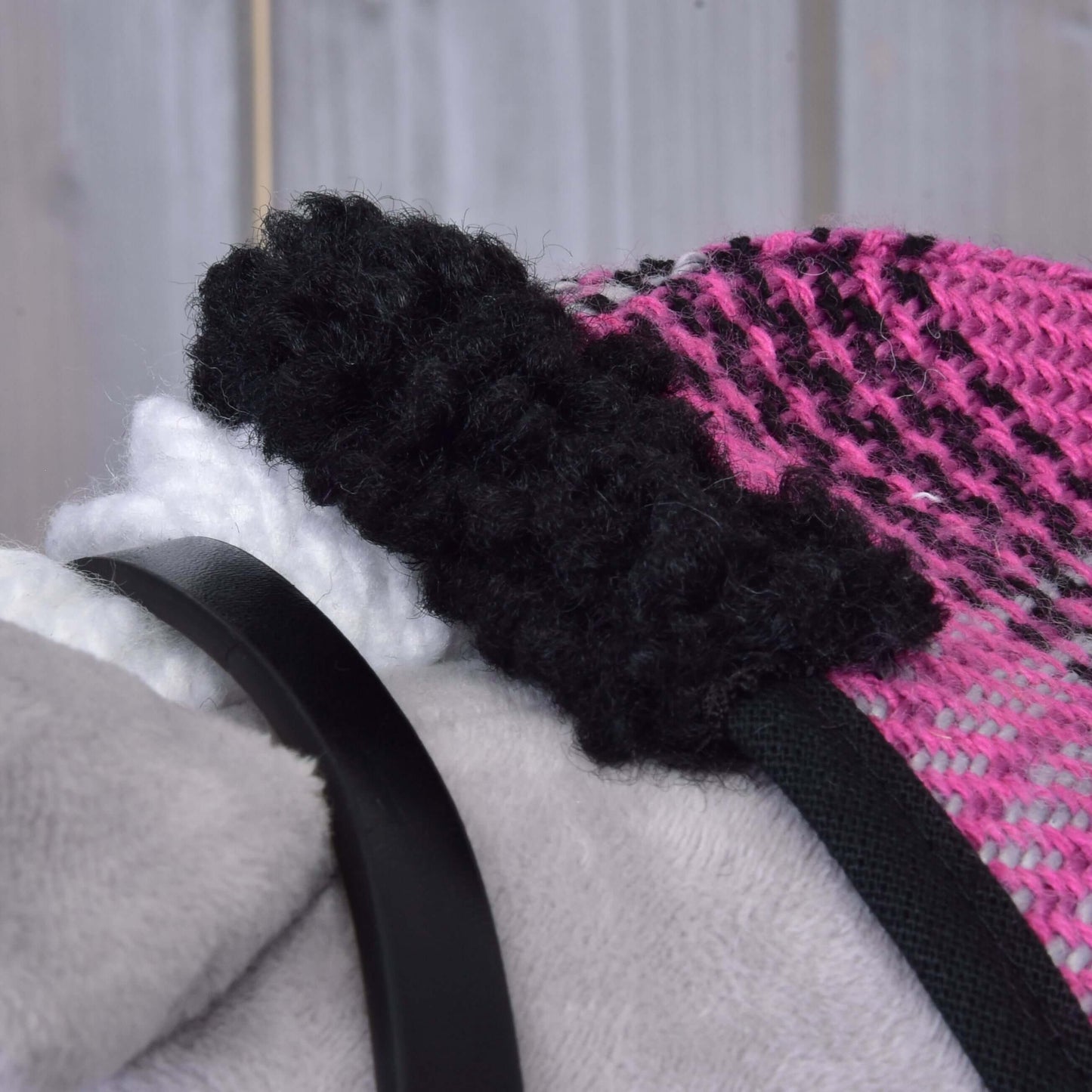 Nahaufnahme von Set Harmony Pink von Hobby Horse LarDen mit pink-schwarzem Strickstoff, flauschigem schwarzem Rand, weißem strukturiertem Detail und glattem schwarzem Halfterriemen vor hellgrauem Hintergrund.