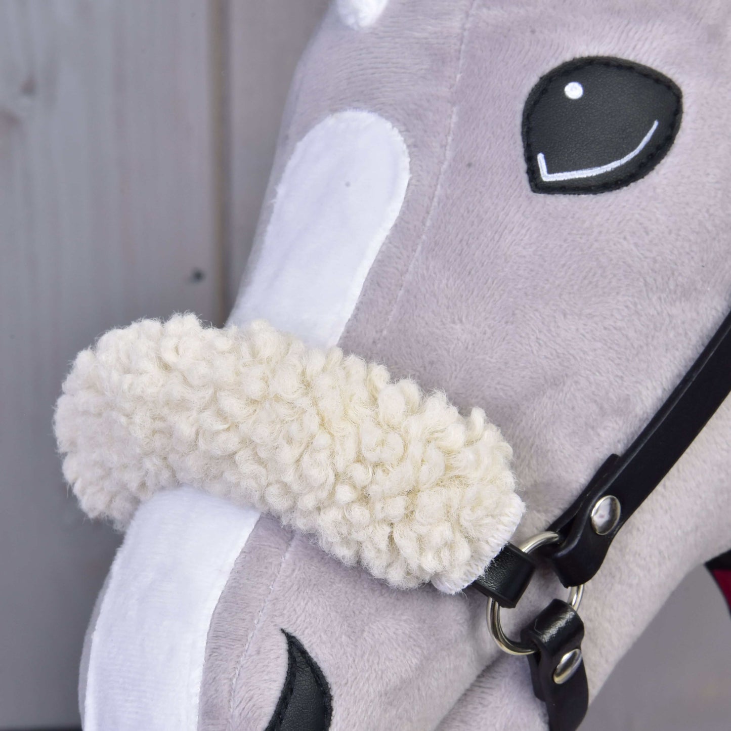 Gros plan sur l’Ensemble Harmonie Victoire de Hobby Horse LarDen, avec tête grise aux accents noirs et blancs, museau blanc et muserolle crème duveteuse sur un licol noir.