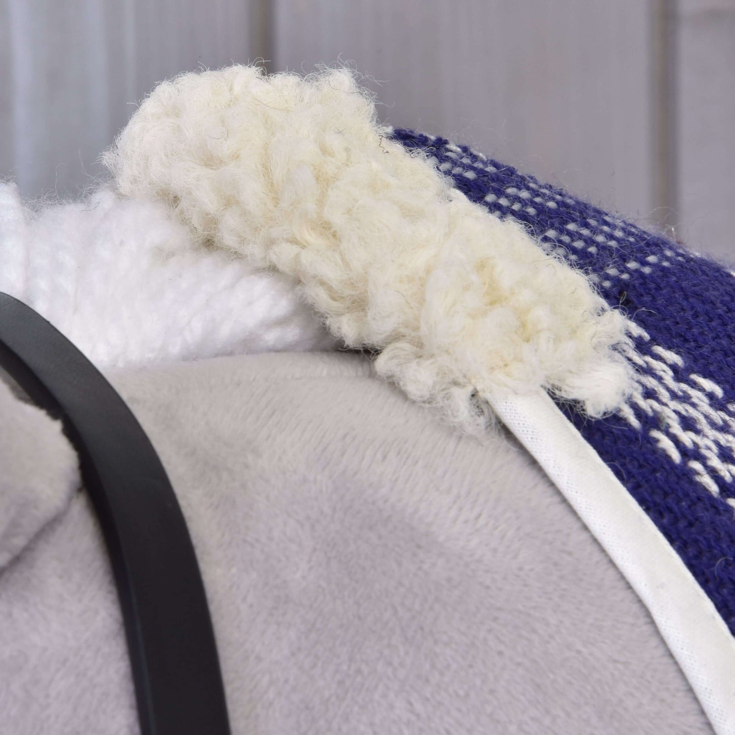 Gros plan sur la doublure douce et confortable en polaire blanche de la couverture d’écurie bleue et blanche Ensemble Harmonie Victoire de Hobby Horse LarDen, montrée avec une surface grise et une sangle noire à proximité.