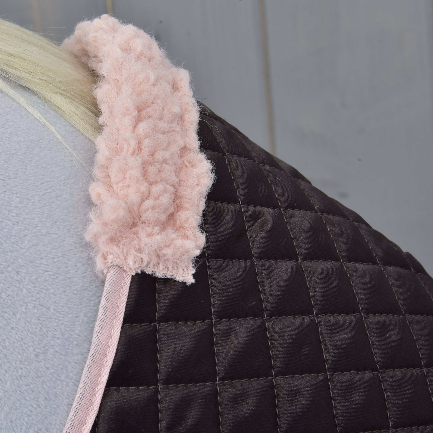 Nahaufnahme von Set Thermo Sweety von Hobby Horse LarDen mit gestepptem dunkelbraunem Stoff und weichem rosa Besatz, über einer hellgrauen Oberfläche drapiert – ideal als elegante Decke oder Dekoration für dein Hobby Horse.
