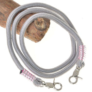 Rênes Tizian de Hobby Horse LarDen en polypropylène gris enroulé avec mousquetons argentés et enroulements rose argenté à chaque extrémité, présentées sur du bois sur fond blanc, idéales comme rênes faites main élégantes ou rênes pour Hobby Horse.