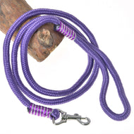The Hobby Horse LarDen "Hobby Horse - rope stripe Viola" features a coiled purple rope leash with a metal clasp, detailed stitching near the clasp and handle, shown lying on wood—perfect as sturdy tethering equipment.