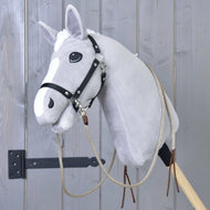 Ein graues Plüsch-Hobby Horse von Hobby Horse LarDen mit Offene Westernzügel Dallas und schwarzem Zaumzeug, auf einem Holzstab montiert, vor einer grauen Holzwand.