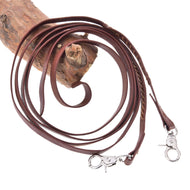 Die Hobby Horse LarDen Offene Westernzügel Dark Brown mit gewickeltem Design und Metallclips an beiden Enden sind auf Holz vor weißem Hintergrund ausgelegt.