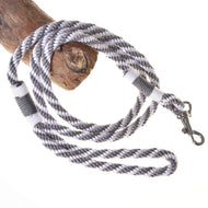 The Hobby Horse LarDen “Hobby Horse - Lead rope stripe silver” is a black and white striped rope with a metal clasp, perfect for leading or lunging hobby horses, shown looped around wood on a white background.