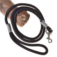 The Hobby Horse LarDen "Hobby Horse - Lead rope black" is a black rope leash with silver reinforced ends and a metal clasp, coiled around a piece of wood.