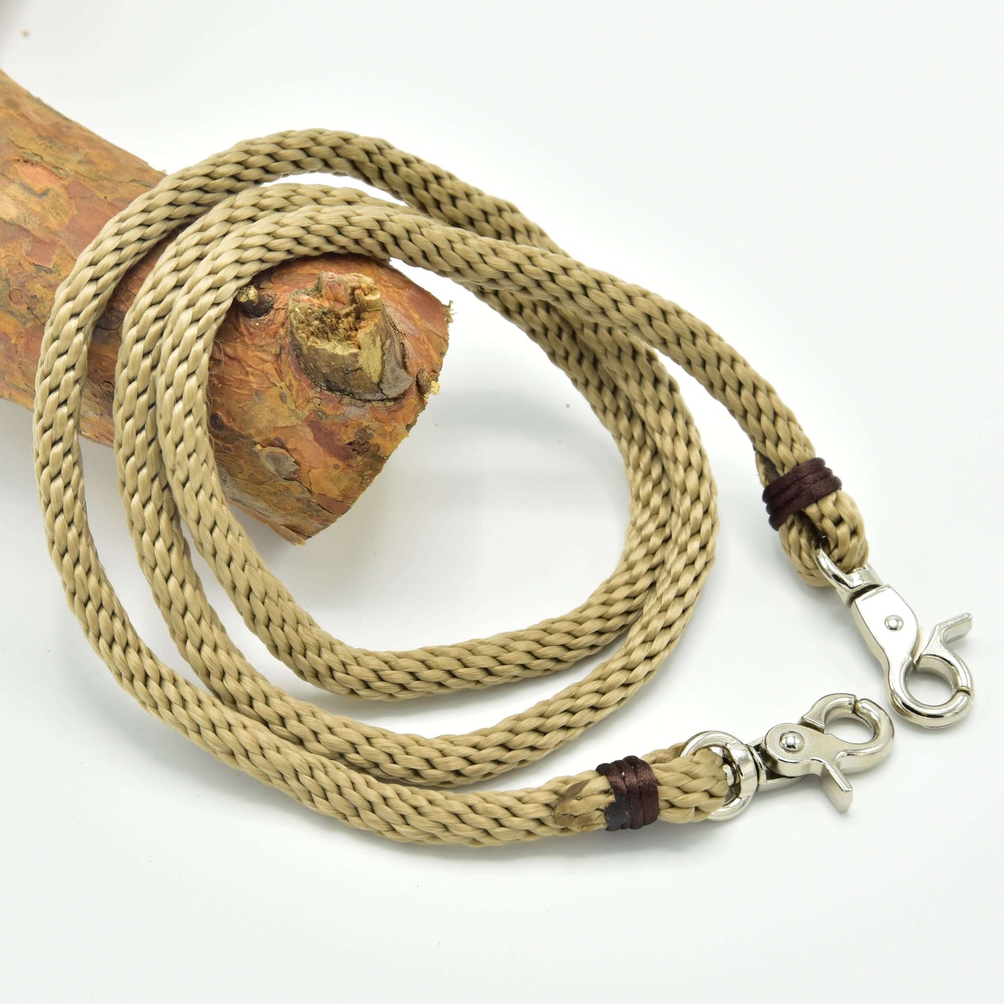 Hobby Horse LarDen Zügel Nature, ein aufgewickeltes, geflochtenes beigefarbenes Polypropylenseil mit Metallkarabinern an beiden Enden, ideal als handgefertigte Zügel für Hobby Horse, auf strukturiertem Holz vor weißem Hintergrund.
